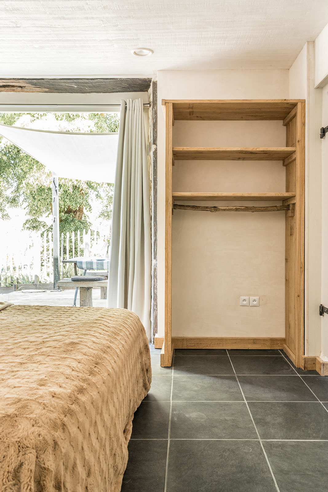 Interieur sfeer vakantiehuis LOTT Coussac-Bonneval binnen slaapkamer boxpringbed openslaande tuindeuren naar terras