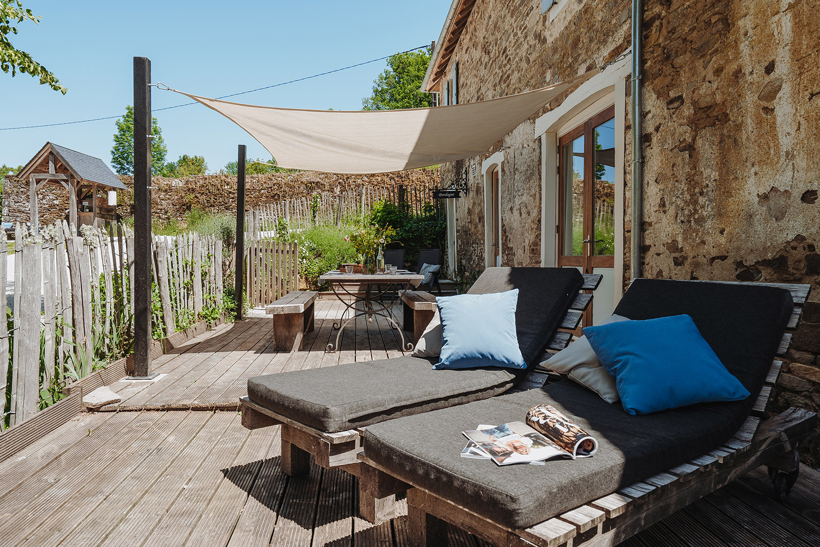 Terras vakantiehuis LOTT Coussac-Bonneval met eettafel stoelen en lounge zonnebedden op vakantiedomein Frankrijk